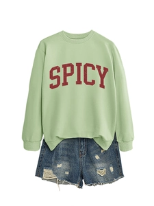 Detail of light green sweatshirt with red SPICY print and distressed denim shorts
