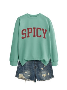 Flat lay of a mint green sweatshirt with red Spicy lettering and distressed denim shorts
