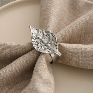 Rustic silver leaf napkin ring with detailed vein texture on a beige linen napkin