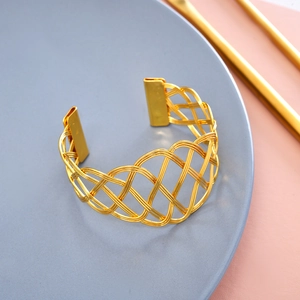 Moderner goldener Serviettenring aus Metallgeflecht auf einem minimalistischen Teller