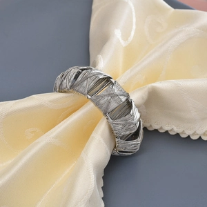 Détail du rond de serviette en fil d'argent tressé sur tissu crème pour décor de mariage