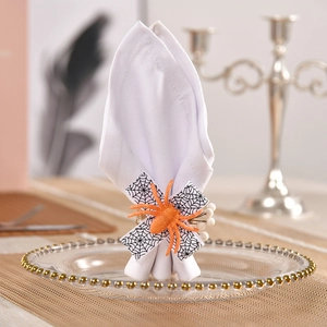 Close-up of glitter orange spider napkin ring with spider web bow on glass plate