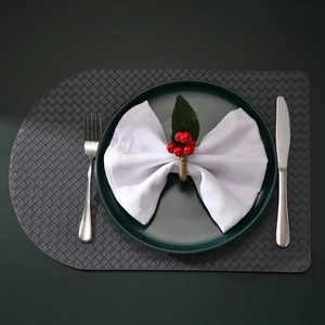 Close-up of a woven D-shaped placemat styled with a festive napkin ring and cutlery