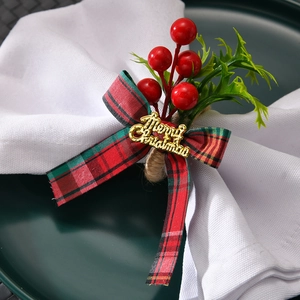 Detail of Christmas napkin ring with red plaid bow, berries and Merry Christmas tag