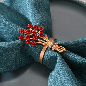 Detailansicht eines Serviettenrings mit roten Rosen und Kristallen auf einem Teller