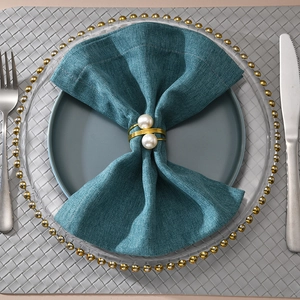 Elegant gold spiral napkin ring featuring double white pearls on blue fabric napkins