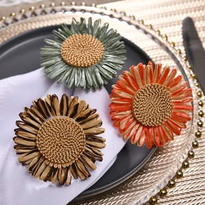 Detail von gewebten Sonnenblumen-Serviettenringen in drei Farben auf elegantem Tisch