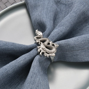 Silver dragon napkin ring on dark blue linen napkin inside a gray ceramic plate