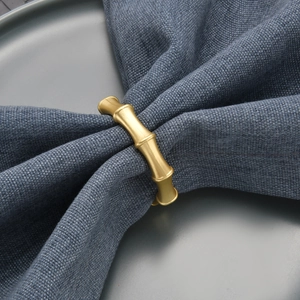 Elegant gold bamboo joint napkin ring on dark blue linen napkin for dining table decor
