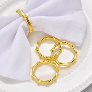 Detailed close-up of golden bamboo-shaped metal napkin rings on white ceramic dinnerware