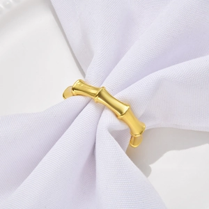 Detailed view of champagne gold bamboo style napkin ring on white wrinkled fabric