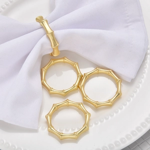 Close-up of golden bamboo joint napkin rings on a white plate for elegant table decor