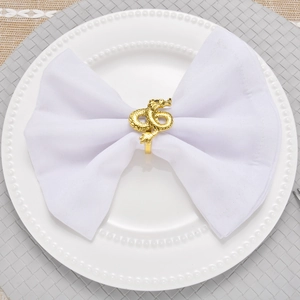 Detailed top view of a gold dragon napkin ring with scales on a white folded cloth