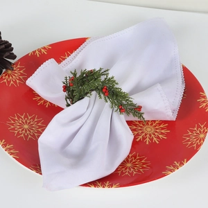 Close-up of a Christmas napkin ring with artificial pine needles and red berries on a plate