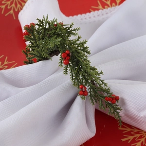 Detail of Christmas napkin ring featuring faux pine needles and red berries decoration