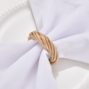 Handcrafted natural rattan woven napkin rings set on white ceramic plates for table decor