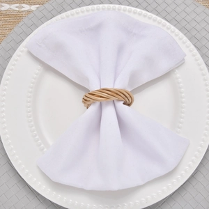 Macro detail of handmade natural rattan napkin ring on a white plate with linen napkin