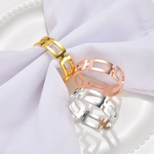 Detail of square geometric napkin rings in gold, silver, and rose gold on a white napkin