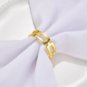 Close-up of a minimalist hollow geometric gold metal napkin ring on white fabric