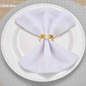 Close-up of golden hollow square geometric napkin ring on a white cloth napkin