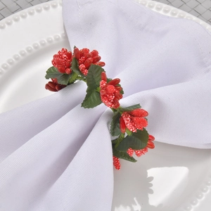Rond de serviette avec baies rouges et feuilles vertes sur une assiette en céramique