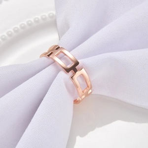 Detailed close-up of rose gold geometric hollow napkin ring on a white cloth napkin