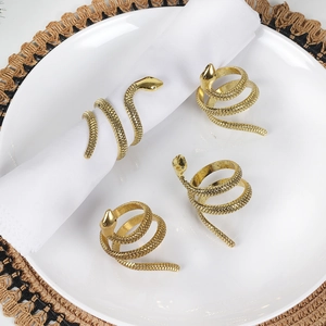 Set of four gold snake napkin rings with spiral scale texture on a white plate