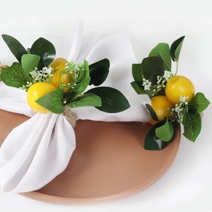 Handmade lemon napkin rings with yellow fruit and green leaves on white napkins