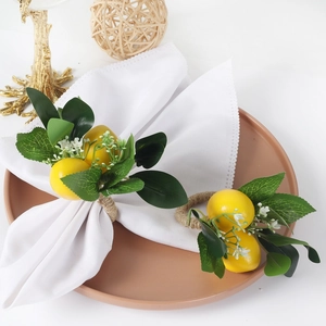 Yellow lemon napkin rings with green leaves and woven rope on a white table napkin