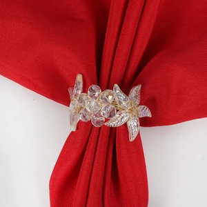 Close-up of a floral crystal napkin ring with gold metal wire on a red fabric napkin