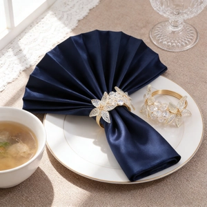 Macro detail of golden metal napkin ring with crystal leaf on a navy blue napkin