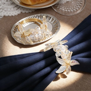 Close-up of golden crystal flower napkin rings on elegant navy fabric and silver tray