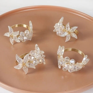 Detail of four gold wire napkin rings with crystal flower beads on a brown tray