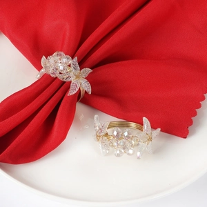 Detail of a gold wire napkin ring with crystal flower beads on a red fabric napkin