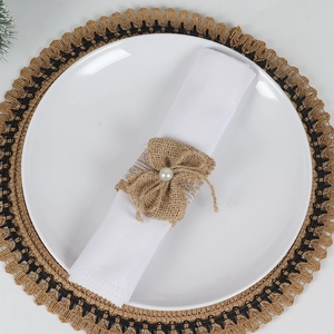 Detail of burlap napkin ring featuring white lace and a central pearl on a white napkin