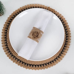 Detail of handmade burlap napkin ring with lace rose on a white plate and woven placemat