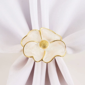 Detail of white enamel flower napkin ring with gold plating for wedding table decor