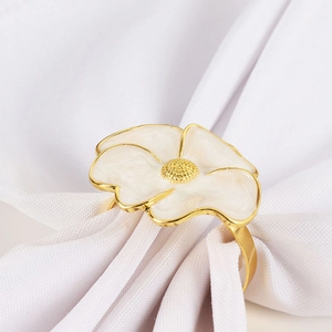 Elegant white enamel flower napkin ring with gold alloy base on a white napkin