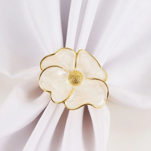 Detailed macro view of white enamel flower napkin ring with elegant gold plating