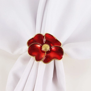 Elegant red flower napkin ring with gold accents on a white cloth for wedding decor
