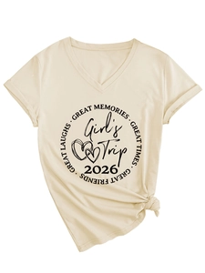 Détail du t-shirt beige à col en V avec imprimé Girl's Trip 2026 et un nœud élégant devant