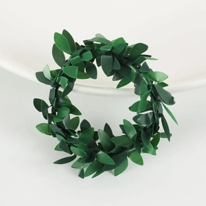 Green vine leaf napkin ring and Christmas garland decoration on minimalist white background