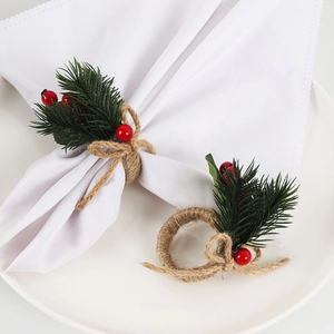 Detail of Christmas napkin ring with pine needles and red berries on a white cloth