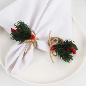 Detail of Christmas napkin ring with pine needles, red berries and jute rope bow