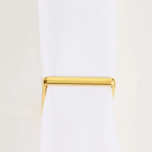 Primer plano de un servilletero cuadrado de metal dorado para decoración de mesa elegante