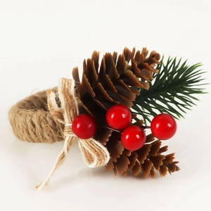 Christmas napkin ring with pine cones, red berries, and twine bow on a white background