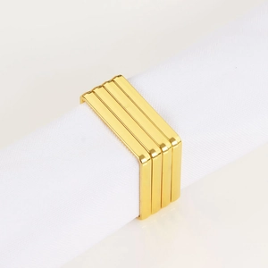 Primer plano de servilleteros geométricos dorados con marcos metálicos rectangulares apilados