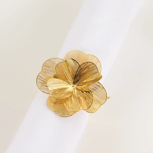 Dettaglio di un portatovaglioli a fiore dorato su tessuto bianco per decoro tavola