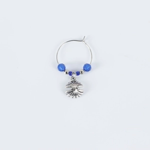 Close-up of silver wine glass charm with dark blue beads and a detailed seashell pendant