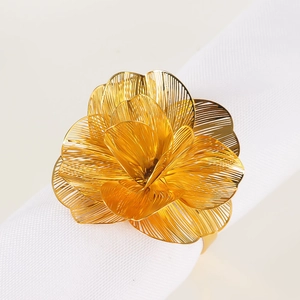 Portatovagliolo a fiore dorato con petali in metallo traforato su tovagliolo bianco